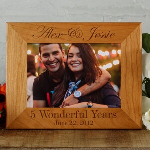May include: A wooden picture frame with a photo of a couple inside. The frame is engraved with the names "Alex & Jessie" and the text "5 Wonderful Years June 22, 2012".