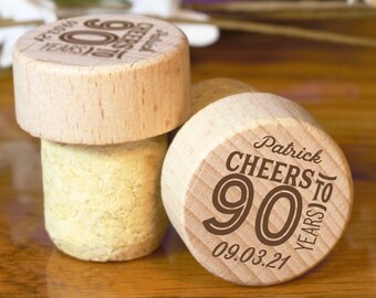 Puede incluir: Dos tapones de botella de madera con texto grabado. Un tapón dice "Cheers to 90 Years" con la fecha 09.03.21 y el nombre Patrick. El otro tapón dice "90 Years Old" con un diseño del número 90.