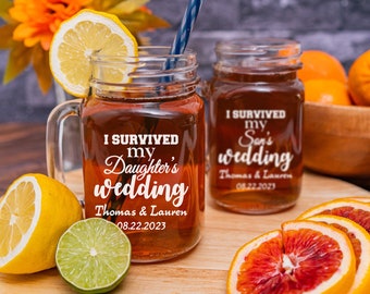 May include: Two mason jars with handles, filled with iced tea, and the text "I survived my daughter's wedding" and "I survived my son's wedding" on them. The jars are on a wooden surface with lemons, limes, and oranges around them.