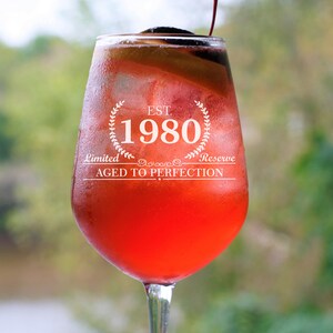 May include: A red wine glass with a white label that reads "EST. 1980 Limited Reserve AGED TO PERFECTION".
