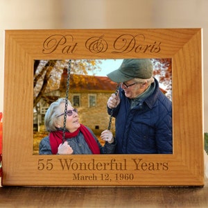 May include: A wooden picture frame with a photo of an older couple on a swing. The frame is engraved with the names "Pat & Doris" and the text "55 Wonderful Years March 12, 1960".