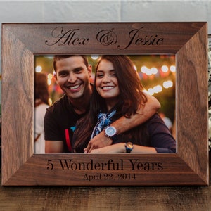 May include: A brown wooden picture frame with a photo of a couple inside. The frame is engraved with the names "Alex & Jessie" and the text "5 Wonderful Years April 22, 2014".
