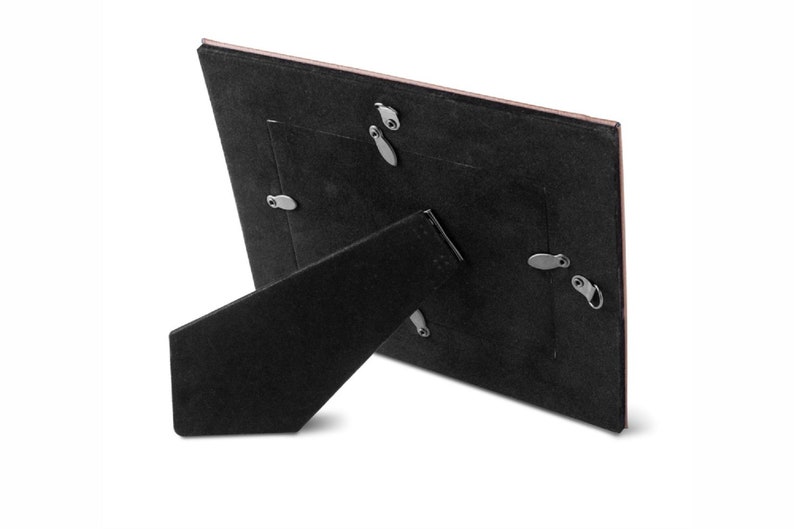 May include: Black picture frame with a brown backing and a stand on the back. The frame has a small opening for a picture.