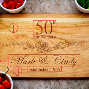 May include: A wooden cutting board with a floral design engraved on it. The board is personalized with the text "50th Anniversary", "Mark & Cindy", and "Established 1965".