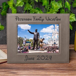May include: A gray picture frame with the text "Peterson Family Vacation" and "June 2024". The frame holds a photo of a statue of Walt Disney and Mickey Mouse in front of Cinderella's castle.
