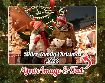 May include: A Christmas ornament featuring a family of three standing in front of a brightly lit Christmas tree. The ornament is personalized with the text "Miller Family Christmas 2023".