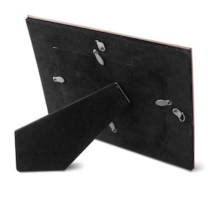 May include: Black picture frame with a brown backing and a stand on the back. The frame has a small opening for a photo.