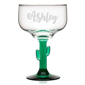 Op de afbeelding: Een helder glazen margarita-glas met een groene cactussteel en -voet. Het glas is gegraveerd met de naam "Ashley".