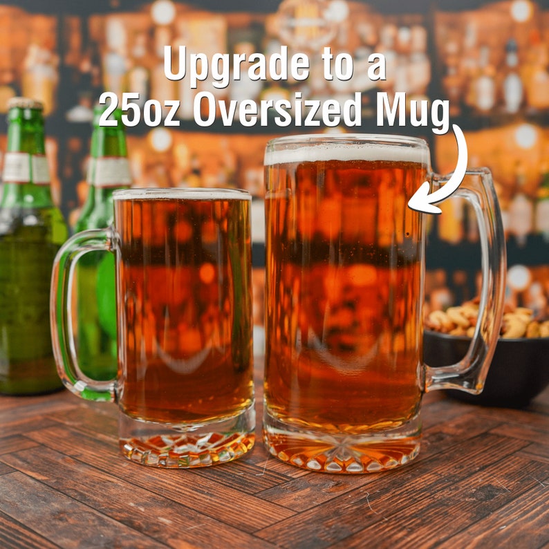 May include: Two glass beer mugs on a wooden table. The mug on the right is larger and has the text "Upgrade to a 25oz Oversized Mug" above it.