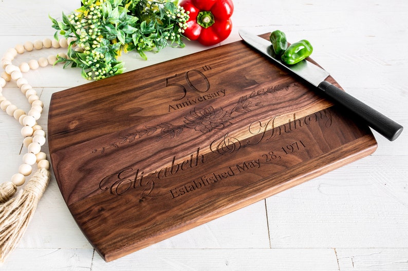 May include: A personalized walnut cutting board engraved with "50th Anniversary", "Elizabeth & Anthony", and "Established May 28, 1971".