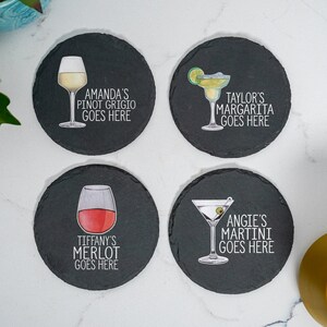 May include: Four black slate coasters with white text and images of different drinks. The coasters feature the text "Amanda's Pinot Grigio Goes Here", "Taylor's Margarita Goes Here", "Tiffany's Merlot Goes Here", and "Angie's Martini Goes Here".