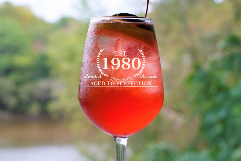 May include: A red wine glass with a white label that reads "EST. 1980 Limited Reserve AGED TO PERFECTION".