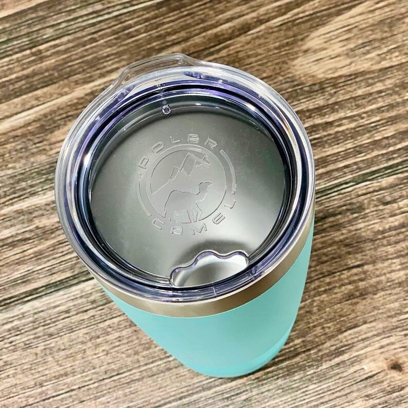 May include: A turquoise travel mug with a silver lid and a clear plastic lid with a silver band. The clear lid has a logo that says "Dolce Brew Co."