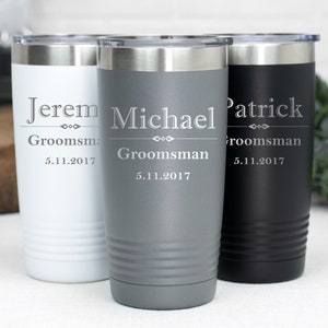 May include: Three stainless steel tumblers with personalised engravings. The tumblers are in white, grey, and black. The engravings include the names "Jerem", "Michael", and "Patrick", the word "Groomsman", and the date "5.11.2017".