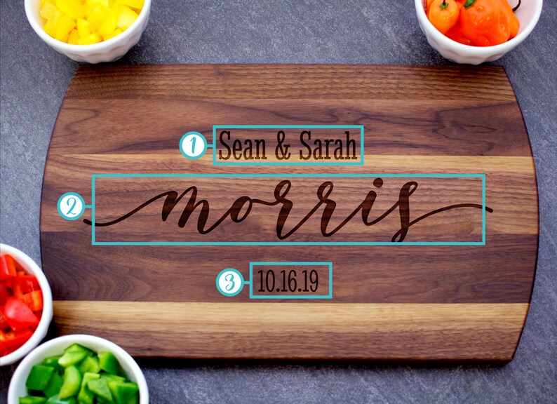 May include: A wooden cutting board with a personalized inscription. The inscription reads "Sean & Sarah Morris 10.16.19".