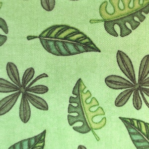 Könnte beinhalten: Grüner Stoff mit einem sich wiederholenden Muster aus braunen und grünen Blättern. Die Blätter sind stilisiert und haben ein tropisches Flair.