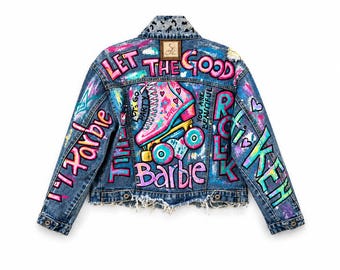 May include: A blue denim jacket featuring colorful hand-painted graffiti art, including a pink roller skate, hearts, and the text "LET THE GOOD TIMES ROLL", "Barbie", and "YOU ARE BEAUTIFUL". The jacket has a frayed hem and leopard print collar.