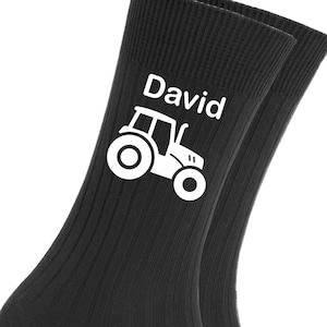 Könnte beinhalten: Ein Paar schwarze Socken mit einem weißen Traktor und dem Namen "David" darauf gedruckt.