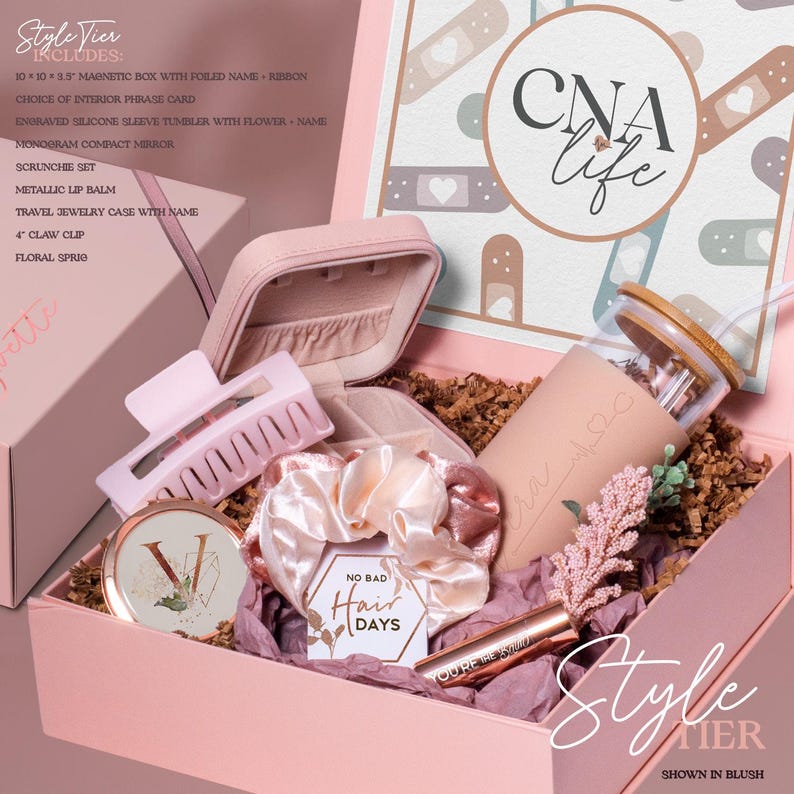May include: A pink gift box with various items, including a tumbler, scrunchie, compact mirror, lip balm, and hair claw. The box has the text "CNA life" and "No Bad Hair Days". The items are arranged on a bed of brown paper.