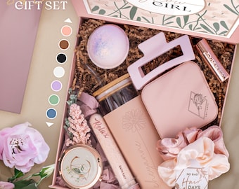 May include: A pink gift box filled with self-care items, including a bath bomb, a hair scrunchie, a bath salt, a tumbler, a makeup bag, and a hair clip. The box is decorated with a floral pattern and the text "You Glow Girl".
