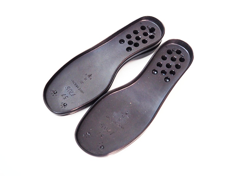May include: Two black shoe insoles with a textured surface and holes. The insoles have the text "7415 SZ 37" printed on them.
