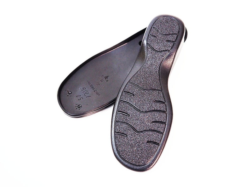 May include: A pair of black shoe soles with a textured tread pattern. The sole on the left has the text "7005 37 1/2" and "MADE IN CHINA" printed on it.