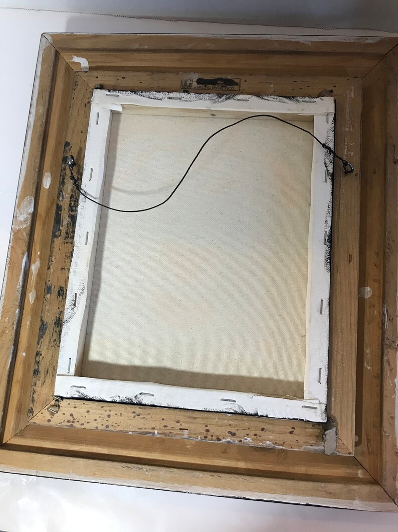 May include: The back of a framed canvas painting with a white canvas and a wooden frame. The frame is a light brown color and has a few dark brown spots on it. There is a black wire attached to the back of the canvas.