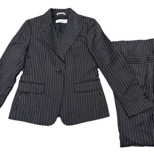 Puede incluir: Una taza de cerámica blanca con un asa negra y el texto "But First, Coffee" en negrita negra. La taza está sobre una superficie de madera. La taza mide aproximadamente 10 cm de alto.