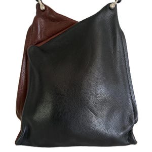 Puede incluir: Un bolso de hombro de cuero negro y marr&oacute;n con una correa negra. El bolso est&aacute; hecho de cuero suave y tiene un dise&ntilde;o simple y minimalista. El bolso es de tama&ntilde;o mediano y parece estar vac&iacute;o.