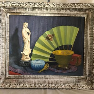 May include: A framed oil painting of a still life featuring a white porcelain figurine, a green folding fan, a blue and white bowl, a gold bowl, and a red box.