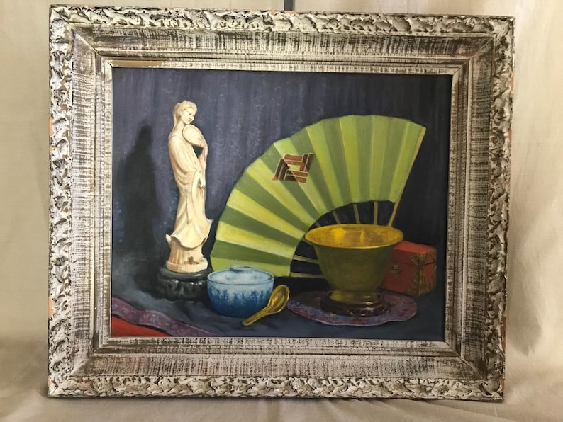 May include: A framed oil painting of a still life featuring a white porcelain figurine, a green folding fan, a blue and white bowl, a gold bowl, and a red box.