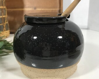 黒の陶器の蜂蜜瓶とひしゃく、黒の釉薬をかけた粘土の陶器の蜂蜜壺
