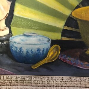 May include: A still life painting featuring a blue and white ceramic bowl, a gold spoon, a gold bowl, and a white statue on a black base. The background is a yellow and green fan.