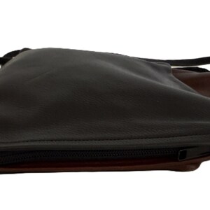 Puede incluir: Bolso bandolera de cuero negro y marr&oacute;n con cierre de cremallera. El bolso tiene un dise&ntilde;o elegante y minimalista con una correa larga y fina. El interior es marr&oacute;n y el exterior es negro. El bolso est&aacute; dise&ntilde;ado para llevarse cruzado.