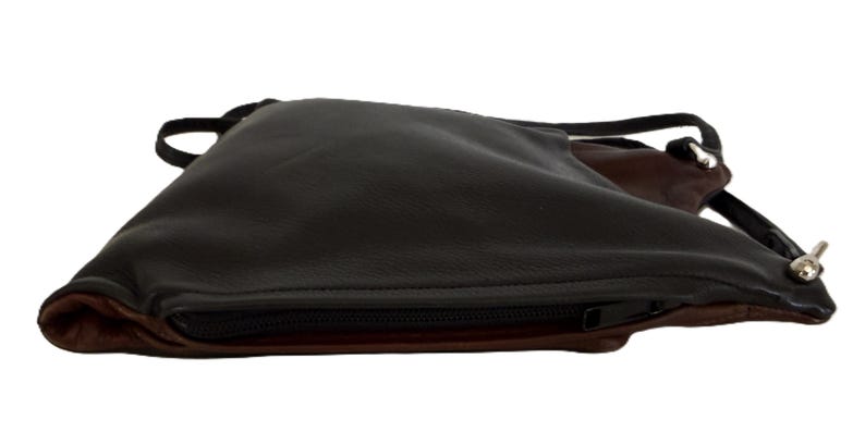 Puede incluir: Bolso bandolera de cuero negro y marr&oacute;n con cierre de cremallera. El bolso tiene un dise&ntilde;o elegante y minimalista con una correa larga y fina. El interior es marr&oacute;n y el exterior es negro. El bolso est&aacute; dise&ntilde;ado para llevarse cruzado.
