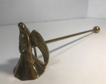 May include: A brass candle snuffer with an angel design. The snuffer has a long handle with a round knob at the end.
