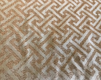 Könnte beinhalten: Nahaufnahme eines gewebten Stoffes mit einem sich wiederholenden geometrischen Muster. Das Design weist ein hellbeige- und cremefarbenes Farbschema auf und erzeugt eine strukturierte Oberfläche. Das Muster besteht aus einer Reihe ineinandergreifender Formen.