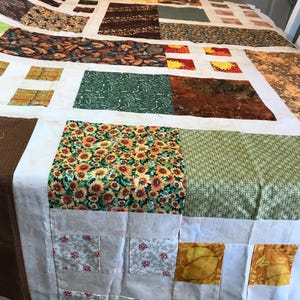 May include: A patchwork quilt with a variety of floral and geometric patterns in shades of brown, green, yellow, and white.