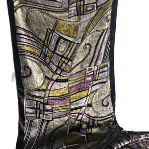Puede incluir: Bufanda decorativa con un diseño geométrico abstracto. La bufanda presenta una textura de terciopelo con una paleta de colores gris, dorado y morado. Los bordes negros enmarcan los bordes, agregando un elemento de contraste.