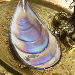 May include: A iridescent glass seashell dish with a gold tray in the background.