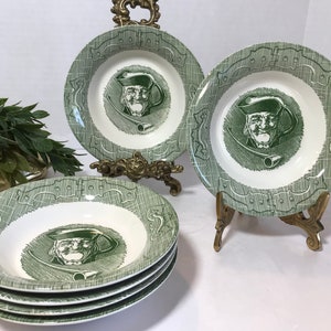 May include: Set of vintage green and white ceramic soup bowls. Each bowl features a green illustration of a man with a pipe. The bowls have a decorative green border and are displayed on brass stands.