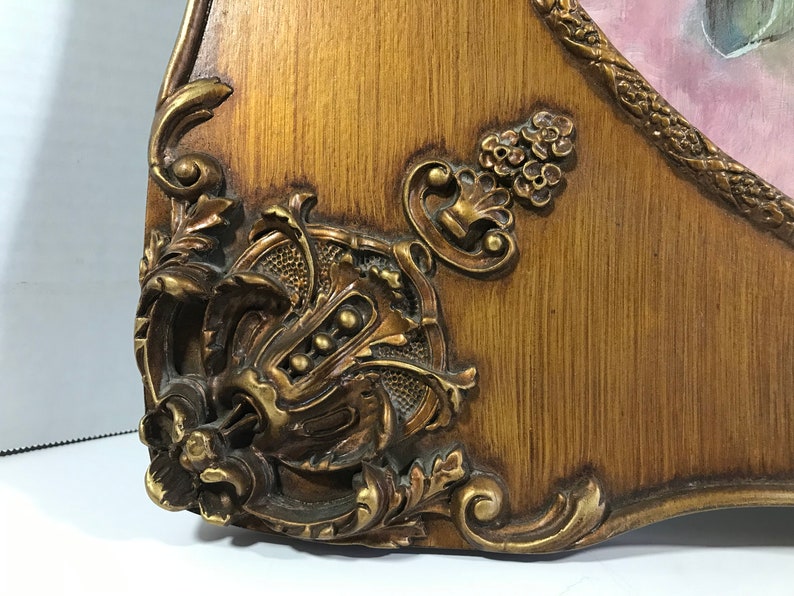 May include: Close-up of a gold-toned ornate frame with intricate carvings and a woodgrain finish.