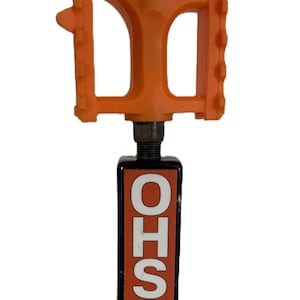 Pode incluir: Um pedal de bicicleta laranja com uma base retangular preta. A base apresenta as letras "OHSO" em branco, com a bandeira do Arizona na parte inferior. O pedal é feito de plástico e tem uma superfície texturizada.