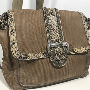 Puede incluir: Un bolso de hombro de lona marr&oacute;n con ribete y hebilla de estampado de piel de serpiente. El bolso tiene cierre de solapa y asa superior.