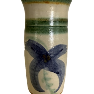 Puede incluir: Un jarrón de cerámica hecho a mano con base crema y un gran diseño floral azul. El borde superior es verde, con una banda verde en el medio. Un jarrón de cerámica único.