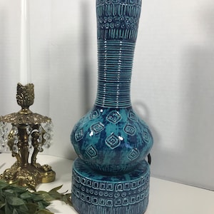 May include: A blue and green ceramic table lamp with a geometric pattern. The lamp has a bulbous base and a tall, cylindrical neck.