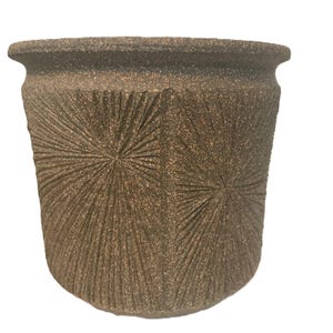 May include: A textured, brown ceramic planter with a wide rim and a starburst pattern carved into the exterior. The planter has a slightly tapered shape and is suitable for indoor or outdoor use.