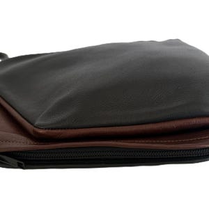 Puede incluir: Bolso bandolera de cuero negro y marr&oacute;n con correa negra. El bolso tiene cierre de cremallera y un dise&ntilde;o en capas, con la capa superior en negro y la capa inferior en marr&oacute;n.