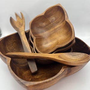 May include: A set of four wooden bowls with a unique cloverleaf shape, perfect for serving snacks or salads. The set includes two wooden spoons and a wooden fork.