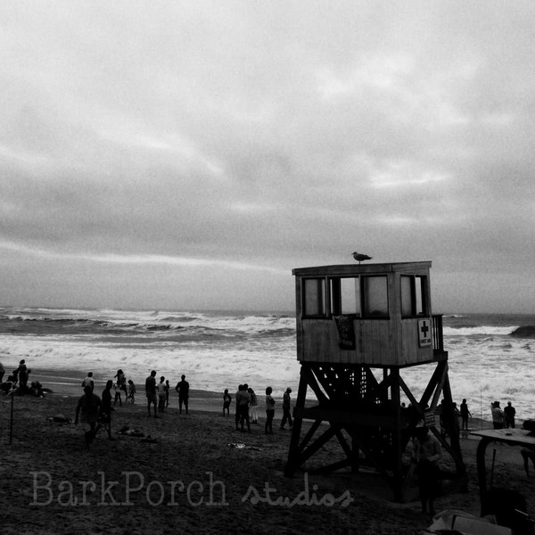 Onlookers watch the incoming hurricane, beside an empty life guard tower; Cape Cod, MA; New England; Black and white; beach house